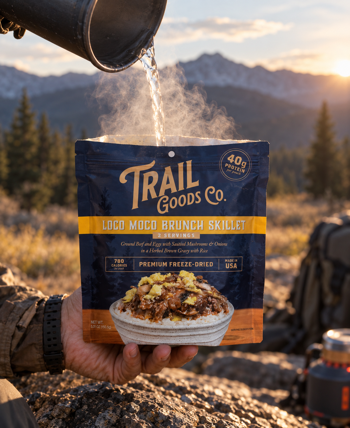 Trail Goods Co. Loco Moco Brunch Skillet pouch held at a mountain campsite while hot water is poured into the open pouch at golden hour.